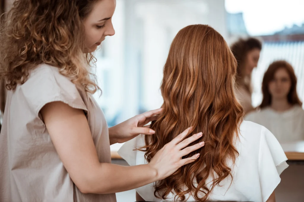 Hairdresser styling long red hair.